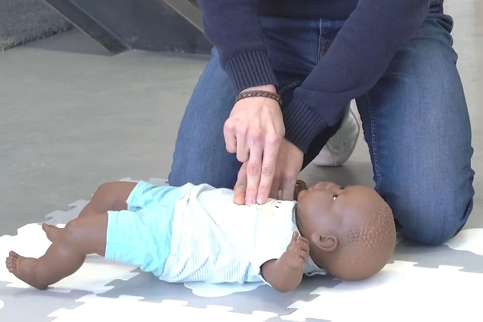 Démonstration d'un massage cardiaque sur un bébé par un sapeur pompier